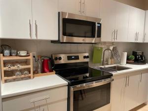 a kitchen with a stove and a microwave at Metrotown Exquisite Entire Suite with 1 Bed Room in Burnaby