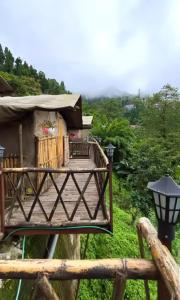 a house with a deck and a lamp at Deoja Forest Stay in Darjeeling