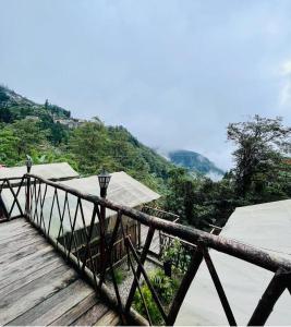 a wooden bridge with a view of a mountain at Deoja Forest Stay in Darjeeling