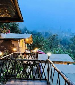 a resort with a balcony with a view of a city at Deoja Forest Stay in Darjeeling