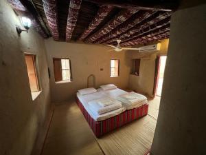 a bedroom with a bed in a room with windows at Mall Aldakhil House in Al Ḩamrāʼ