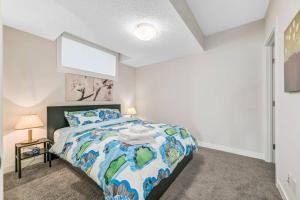 a bedroom with a bed with a blue and white comforter at Brand New Executive Suite in Calgary
