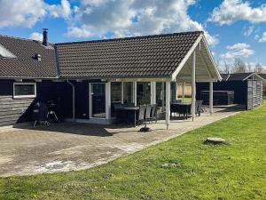a house with a patio with a table and chairs at 14 person holiday home in Idestrup in Marielyst