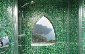 a bathroom with a green tiled wall with a window at Auditorium Rooms in Ravello