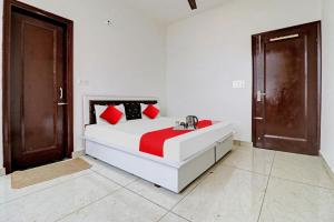 um quarto branco com uma cama grande e almofadas vermelhas em OYO Flagship Hotel Royal Inn em Patiala