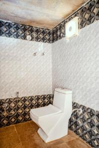 a white toilet in a bathroom with black and white tiles at Desert Safari Camp & Resort Sam in Sām