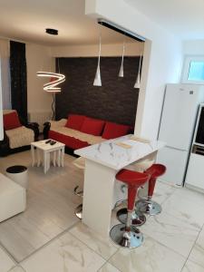 a living room with a white counter and red stools at Bella apartman in Mladenovac