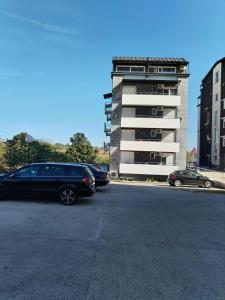 un estacionamiento con autos estacionados frente a un edificio en Bella apartman, en Mladenovac