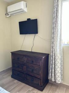 a bedroom with a dresser and a tv on the wall at Los Tres Pinos in Guatemala
