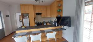 a kitchen with a counter with white chairs and a television at Grey-door cottage Number1 in Glendinningvale +6 photos