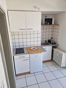 una pequeña cocina con armarios blancos y azulejos blancos en VringsVeedel, en Colonia