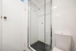 a shower with a glass door next to a toilet at The Allegra - 180 degree ocean and city views in Fremantle