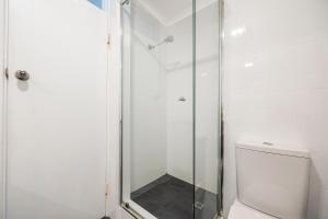 a shower with a glass door next to a toilet at The Allegra - 180 degree ocean and city views in Fremantle +56 photos