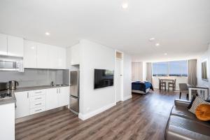 uma cozinha e sala de estar com armários brancos e um sofá em The Allegra - 180 degree ocean and city views em Fremantle