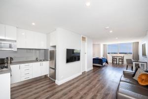 a kitchen and living room with white cabinets and a couch at The Allegra - 180 degree ocean and city views in Fremantle