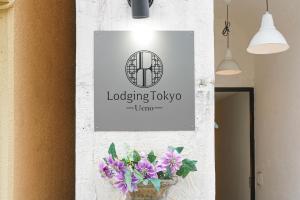 东京Hostel Lodging Tokyo Ueno的花瓶里紫色花的墙上的标志