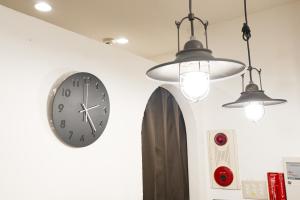 eine Uhr an einer weißen Wand mit zwei Lichtern in der Unterkunft Lodging Tokyo Ueno in Tokio