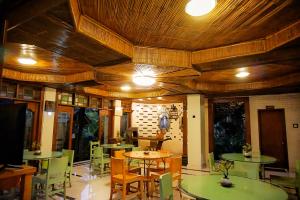 a dining room with tables and chairs and wooden ceilings at Ary's Hotel by Cocotel in Yogyakarta