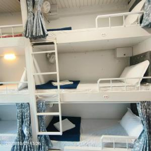 a bunk room with white bunk beds in it at Marol Metro Dormitory in Mumbai