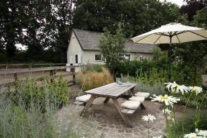 Riel的住宿－Het Rooversnest，一张木制野餐桌和一把带雨伞的椅子