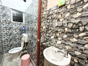 a bathroom with a stone wall with a toilet and a sink at Pocket Friendly 3BHK Apt behind Acropolis Mall in Kolkata
