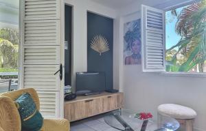 a living room with a tv and a window at La Kaz à MaLou appartement de standing avec piscine et plage à 800m in Les Trois-Îlets