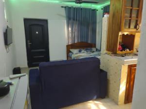 Zimmer mit einem blauen Stuhl in einem Zimmer mit einem Bett in der Unterkunft Kingee Lodge in Sunyani