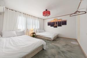 a bedroom with two white beds and a chandelier at Hapjeong station exit7 modern house in Seoul