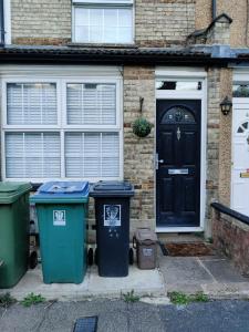 uma casa com três latas de lixo em frente a uma porta em House with great location near Harry Potter studio em Watford