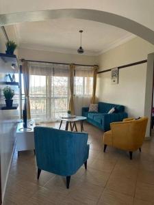 a living room with a blue couch and chairs at Chayil Loft Mulago in Kampala