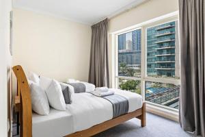 a bedroom with a bed and a large window at StoneTree - Stylish 2BR with Dubai Marina Canal View in Dubai