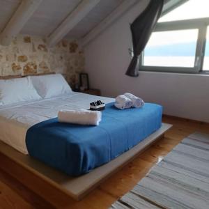 a bed with a blue blanket and shoes on it at Villa VaKo in Vathí
