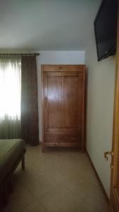 a bedroom with a wooden door and a television at Edelweiss in Valli del Pasubio