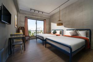 峴港的住宿－La Maison Des Délices，一间卧室设有两张床、一张桌子和一个窗口。