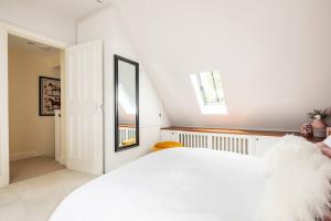a bedroom with a white bed and a mirror at 18th Century Converted Coach House 