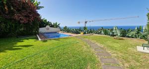 einen Pool in einem Garten mit Meer im Hintergrund in der Unterkunft Sunny Arco Retreat in Arco da Calheta