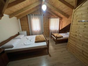a bedroom with two beds in a wooden cabin at Vila Pepaj Razem in Razëm