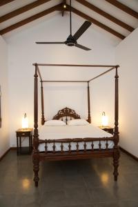 a bedroom with a canopy bed with a ceiling fan at The Mango Nest in Jaffna