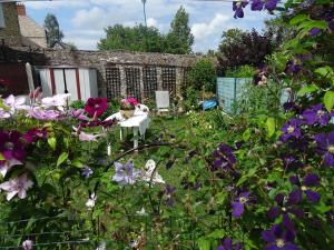un jardín con flores púrpuras, mesa y sillas en Chambre bleue bien équipée chez Fred, en Gorron