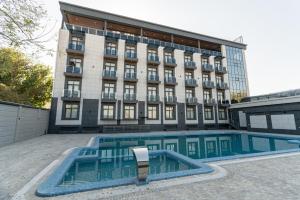 a hotel with a swimming pool in front of a building at Rayyan Hotel & SPA Tashkent in Tashkent