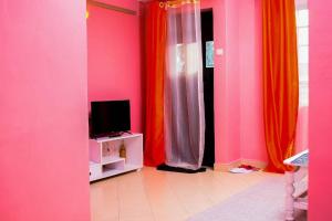 een kamer met roze en oranje gordijnen en een tv bij EP Home in Meru