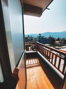eine Person mit Blick aus dem Fenster eines Balkons in der Unterkunft Nishan Apartments -Lakeside in Pokhara