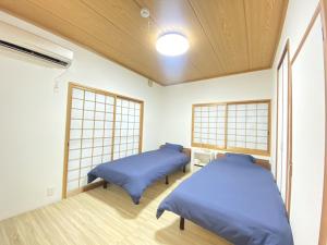 two beds in a room with two windows at 島の宿　結んちゅ in Amami
