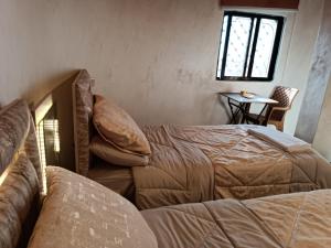 Zimmer mit 2 Betten, einem Tisch und einem Fenster in der Unterkunft hostel ـ Karak dream in Kerak