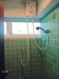 a shower in a green tiled bathroom with a blow dryer at Nearthepark Backpack Hostel 2 in Chiang Mai
