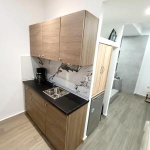 uma pequena cozinha com um lavatório e armários de madeira em Navarino Jacuzzi Studio RT Hospitality Services em Tessalônica
