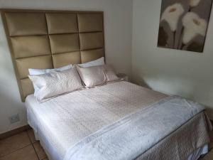 1 dormitorio con 1 cama con sábanas y almohadas blancas en 27 @ Wozani Ridge en Hibberdene