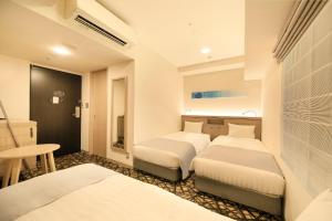 um quarto de hotel com duas camas e uma mesa em S-peria Inn Osaka Hommachi em Osaka