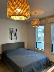 een slaapkamer met een bed, 2 verlichting en 2 ramen bij Studio Design & Cosy avec Parking in Issy-les-Moulineaux