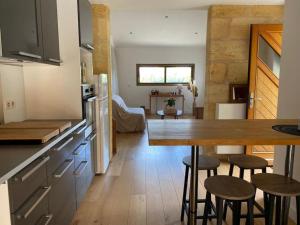 una cucina con tavolo e alcuni sgabelli in una stanza di Le Shala - 55m² + Jardin a Tabanac